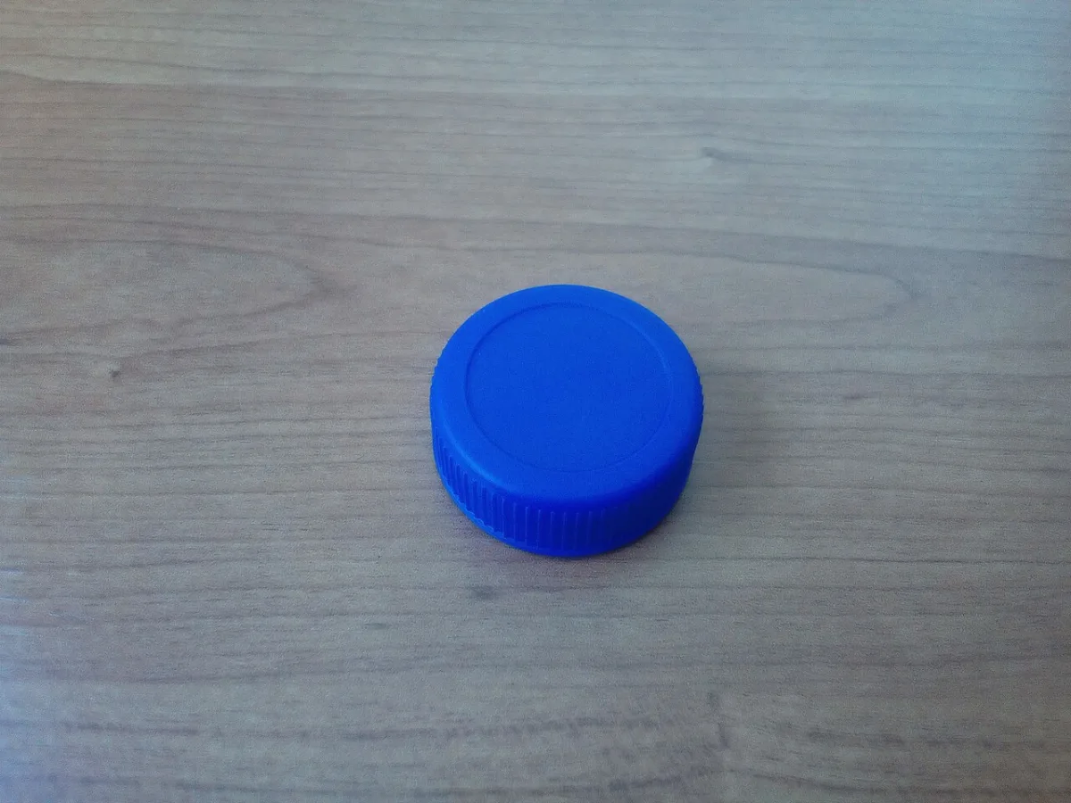 Blauwe kunststof flessendop op een houten ondergrond